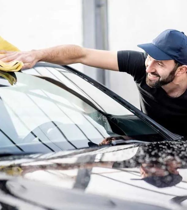 Dan washing a car and smiling