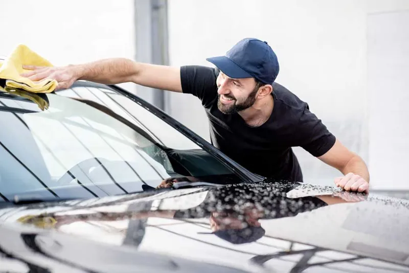 Hand washing the exterior of a car with soap and a wash mitt