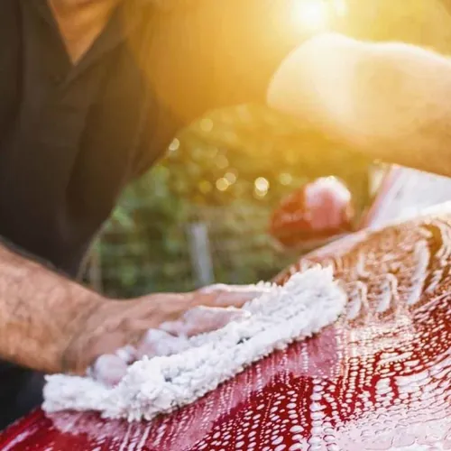 Detailer washing the hood of a car